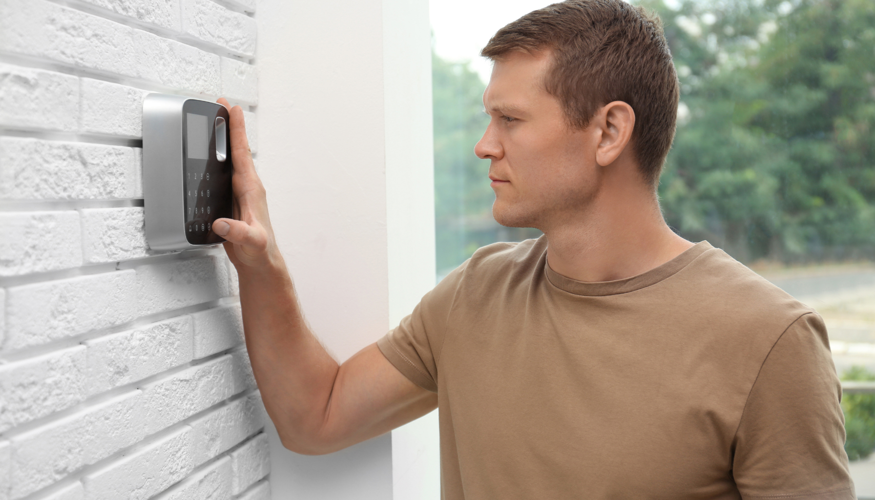 Un homme entre son code dans son boitier d'alarme sans fil pour sécuriser son habitation